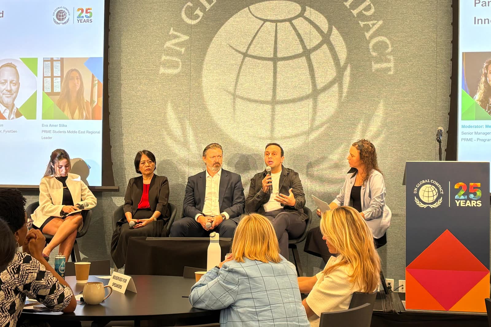 Five panellists seated on stage in front of a UN Global Compact backdrop, one of them speaking into a microphone