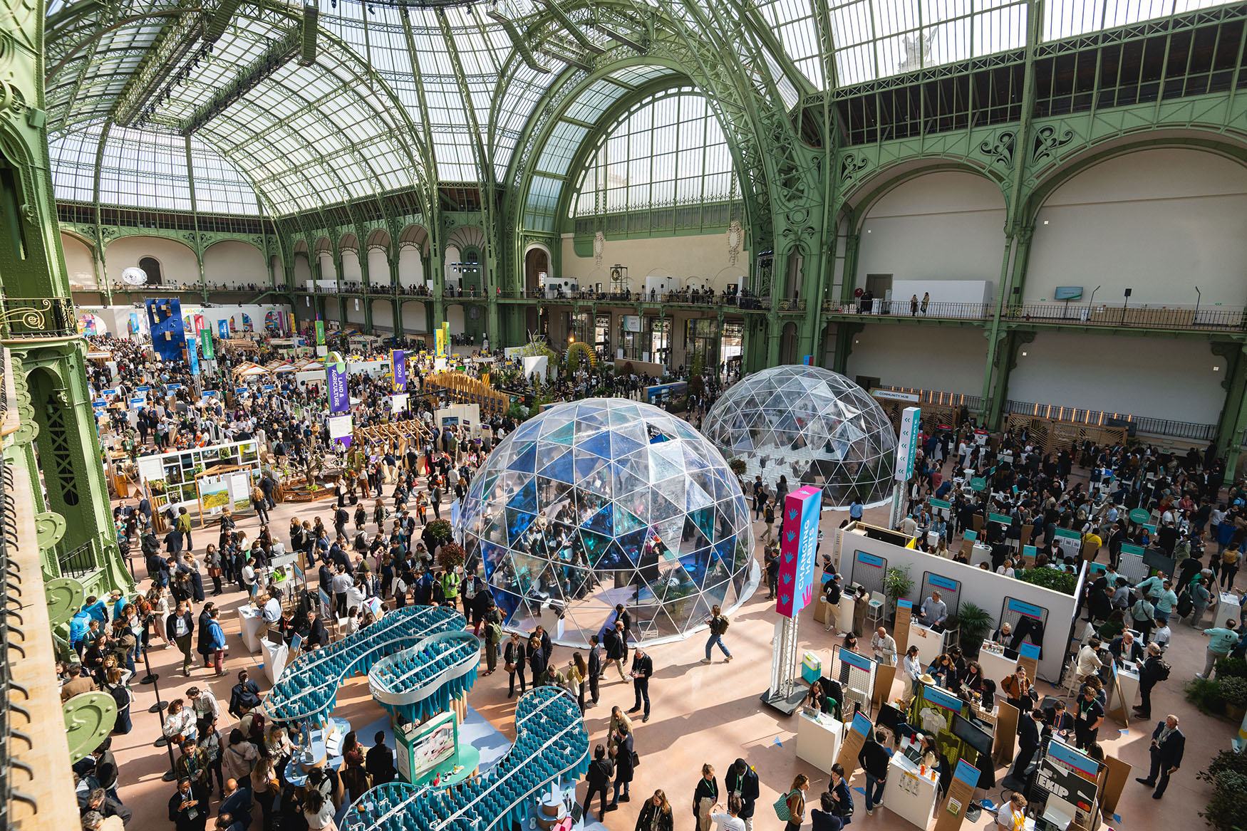 Crowds at an exhibition beneath a historic glass roof