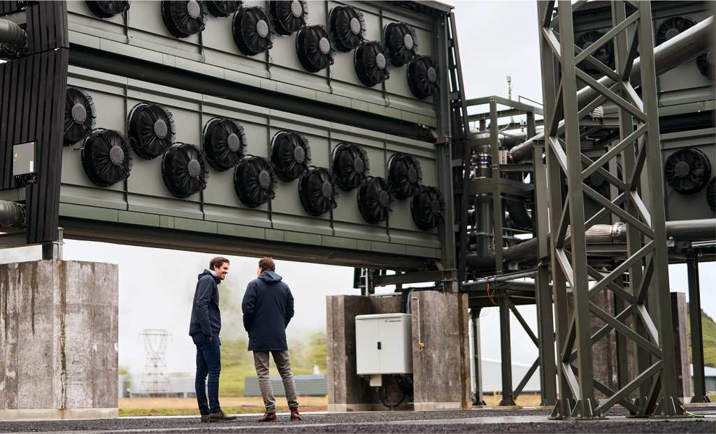 Two people standing in front of rows of industrial carbon capture fans