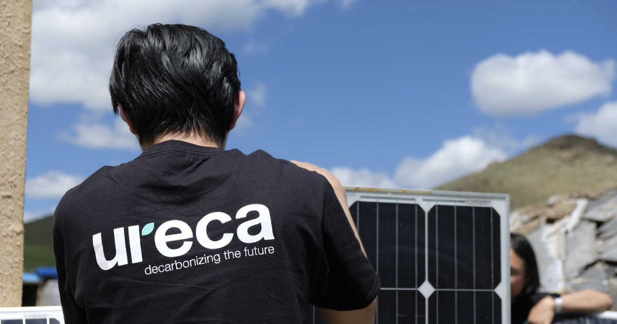 A person in a URECA jacket standing in front of solar panels