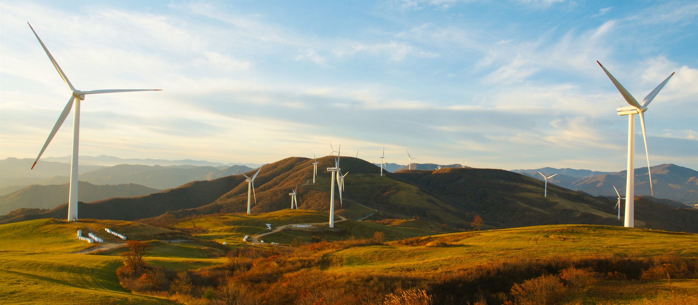 Wind turbines on green hillsides at sunrise